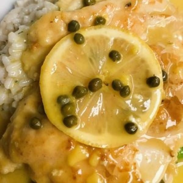Close-up of Bacco Ristorante's chicken piccata with lemon, capers, and a side of rice.
