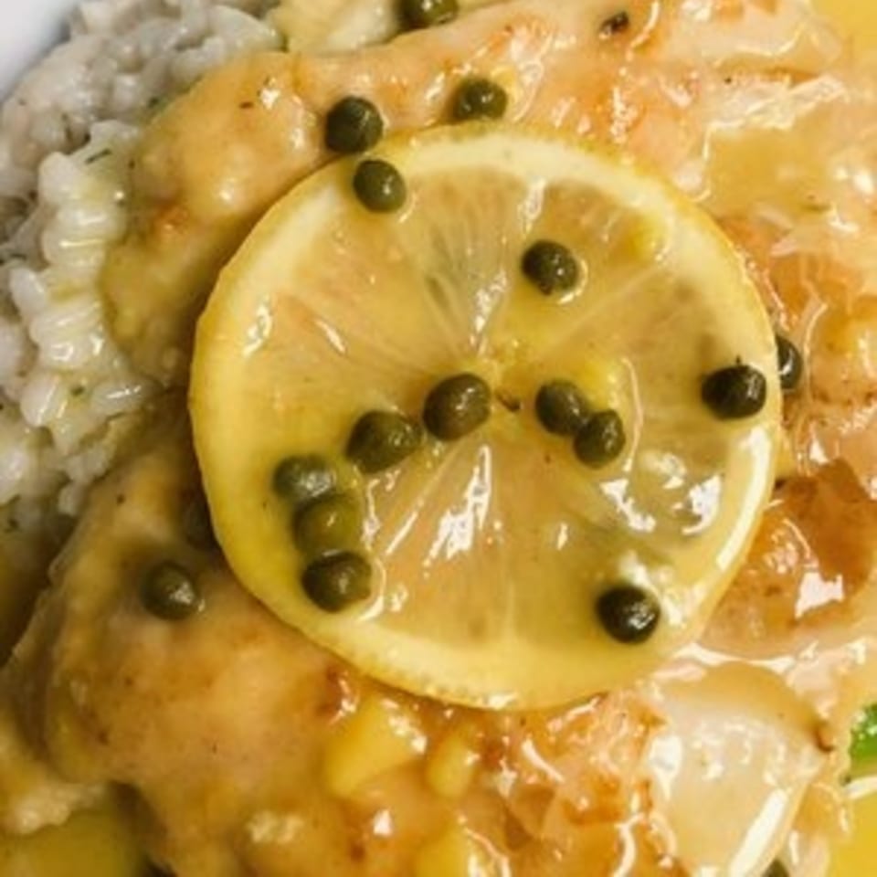 Close-up of Bacco Ristorante's chicken piccata with lemon, capers, and a side of rice.