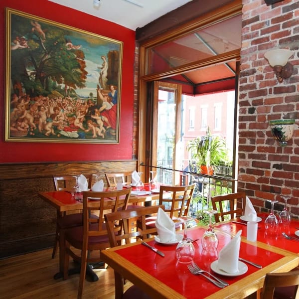Bacco Ristorante & Bar's dining room with red walls, a large painting, and set tables.