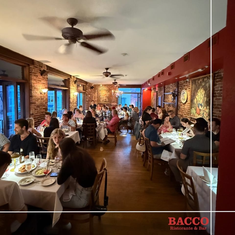 Diners enjoying meals at Bacco Ristorante & Bar, with exposed brick walls and ceiling fans.