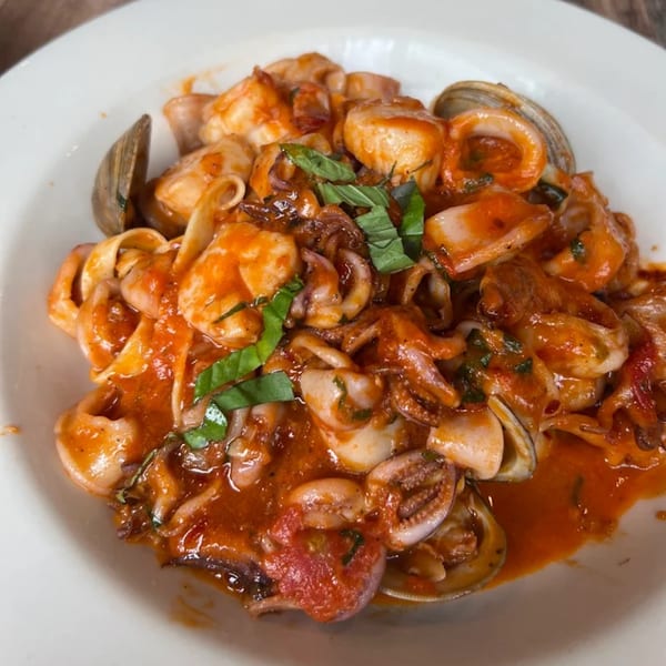 Bacco Ristorante & Bar's seafood pasta with clams, calamari, and shrimp in red sauce, garnished with basil.